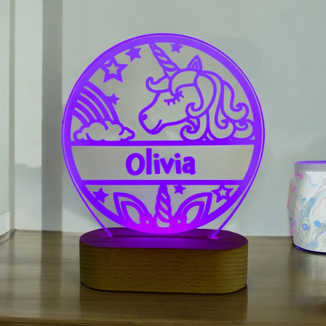 Enhjørning lampe med navn og lilla LED lys på træfod.