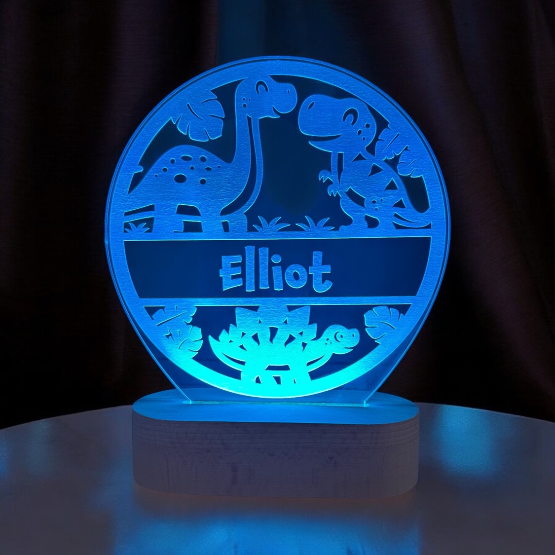 Dino lampe med navn og blå LED lys. På træfod.