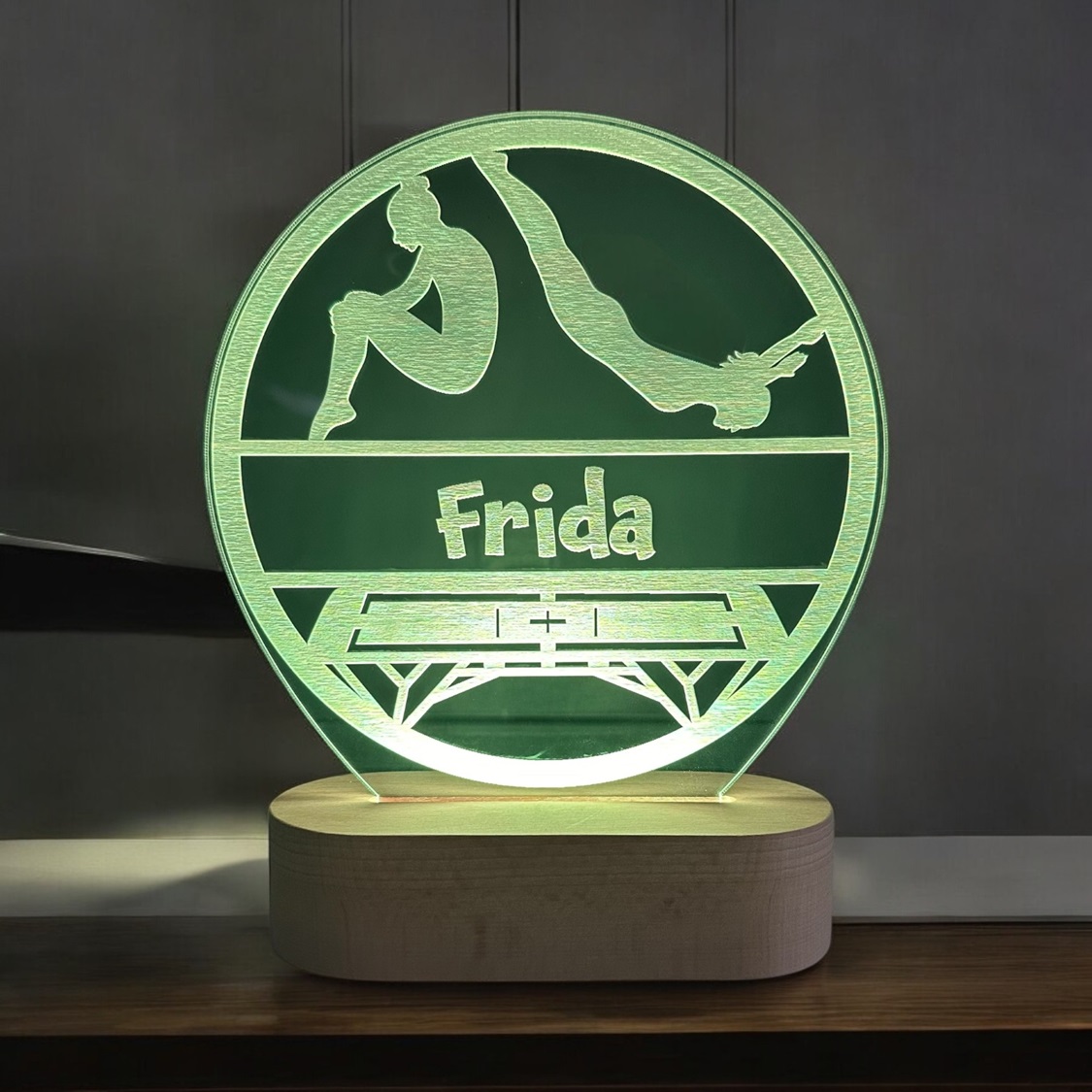 Gymnastik lampe med navn og gul LED lys. På træfod.