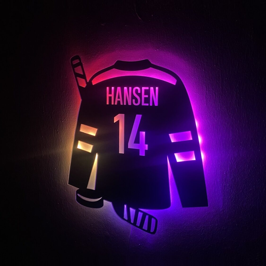 Ishockey lampe formet som en spillertrøje med navn og nummer. Der er også en ishockeystav og en puk. Lyses op med LED i flere farver.